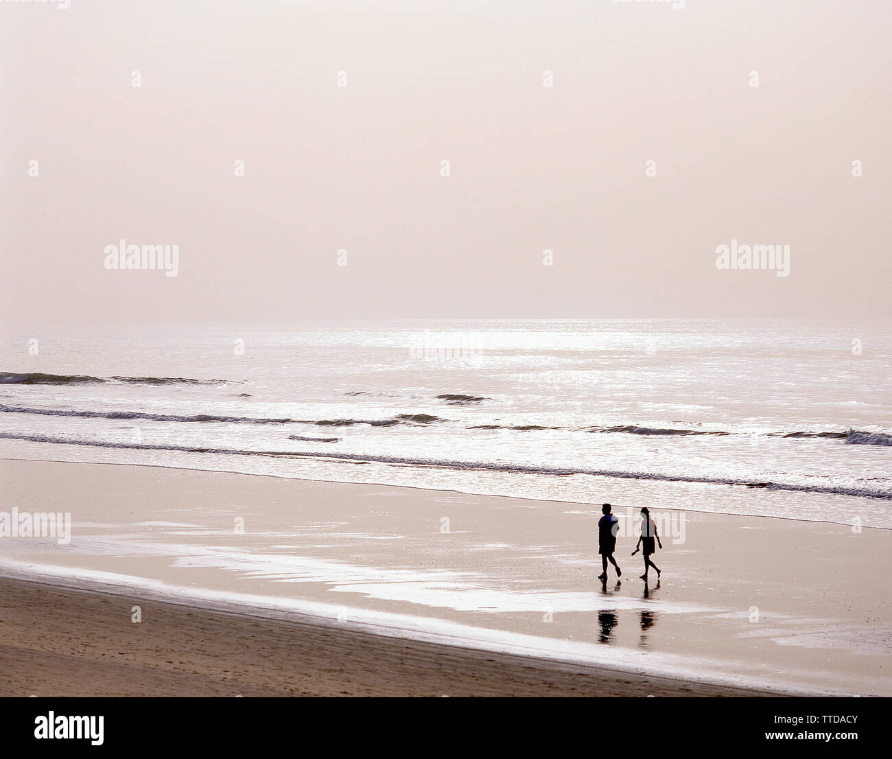 Giovane camminando sulla spiaggia al tramonto, Serrekunda spiaggia (Senegambia Beach Hotel), Serrekunda, Repubblica della Gambia Foto Stock