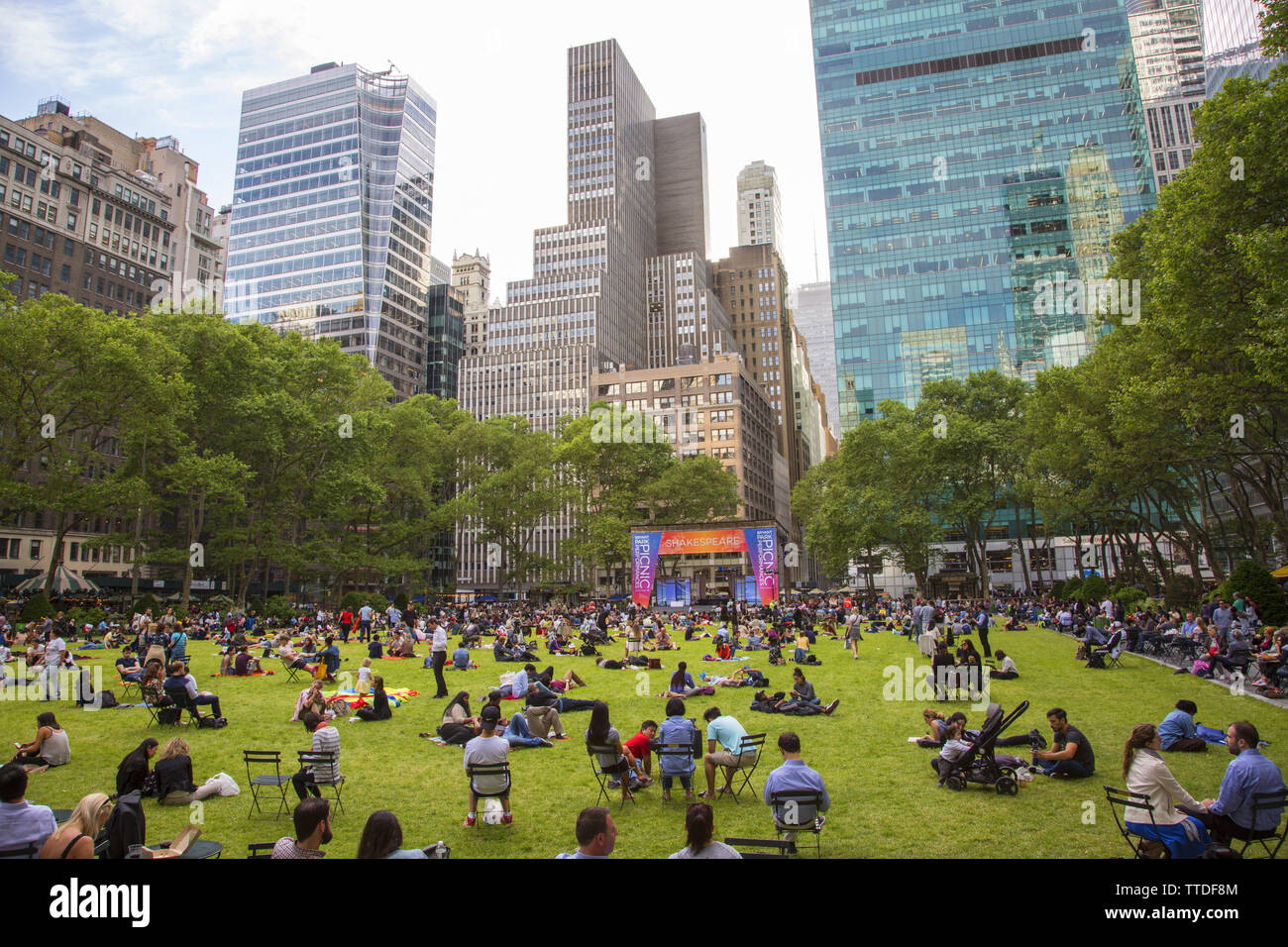 I turisti e i newyorkesi simili rilassarsi sull'erba a Bryant Park dietro la Biblioteca Pubblica di New York lungo la 42nd Street tra la quinta e la sesta sedi a th Foto Stock