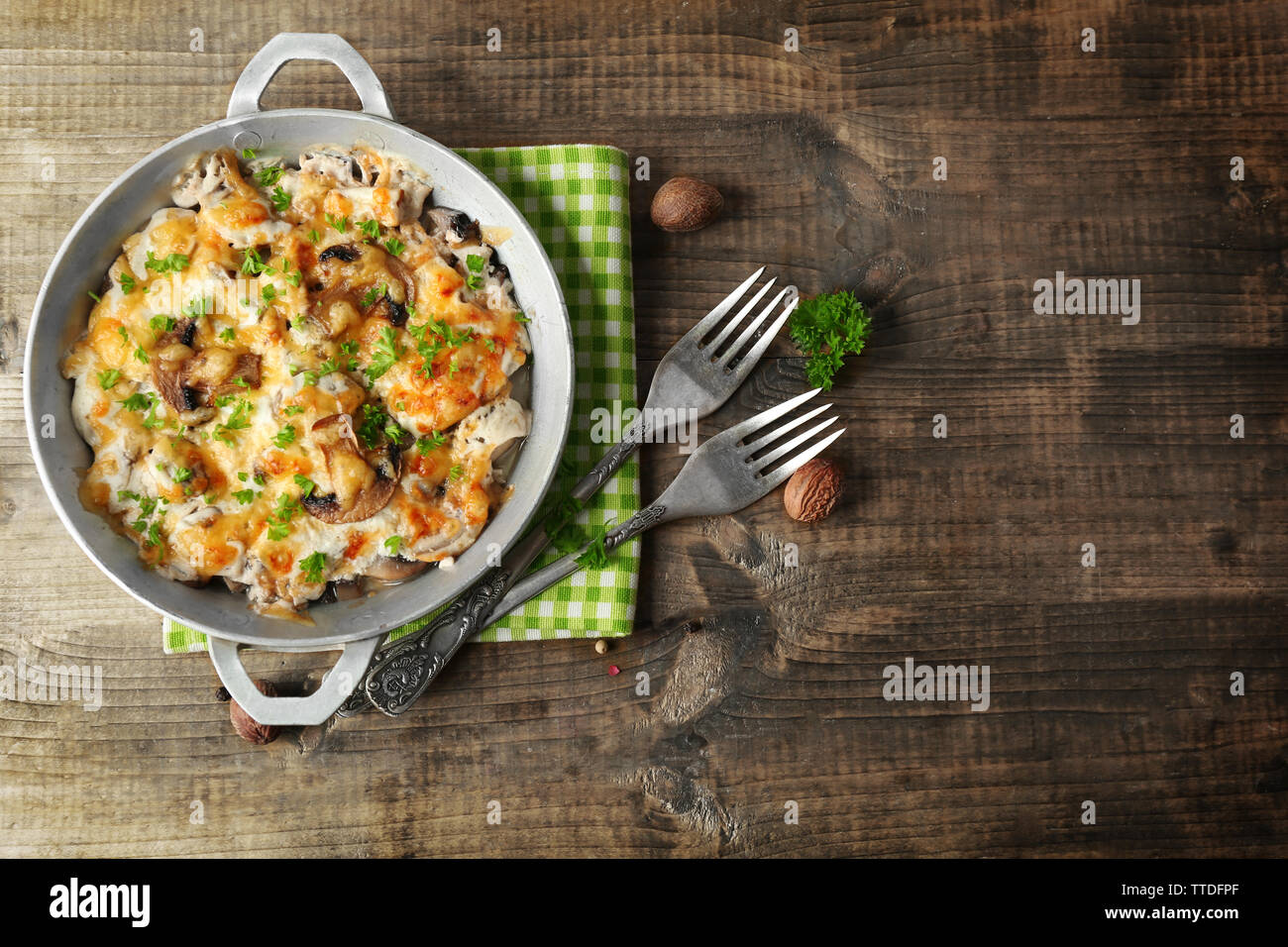 I funghi porcini arrosto, carne di pollo e formaggio gratinato in padella, su sfondo di legno Foto Stock