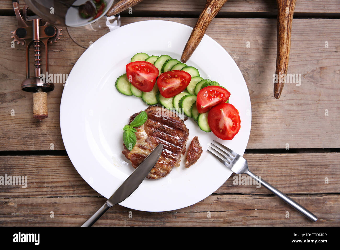 Arrosto di filetto di cervo e di verdure fresche sulla piastra, su sfondo di legno Foto Stock