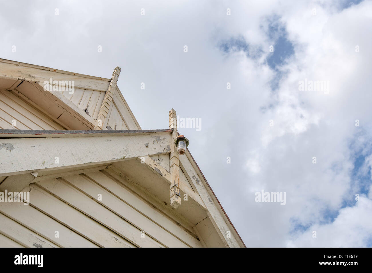 Scudo ornato tavole dipinte di color crema e un vecchio portico esterno luce su una chiesa in legno nel Nuovo Galles del Sud, Australia Foto Stock