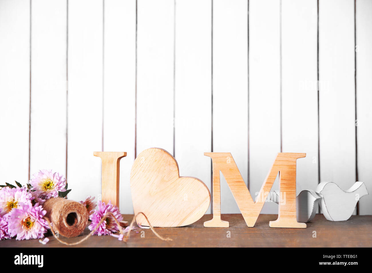 Lettere di legno con il cuore e con fiori di colore bianco su sfondo a parete Foto Stock