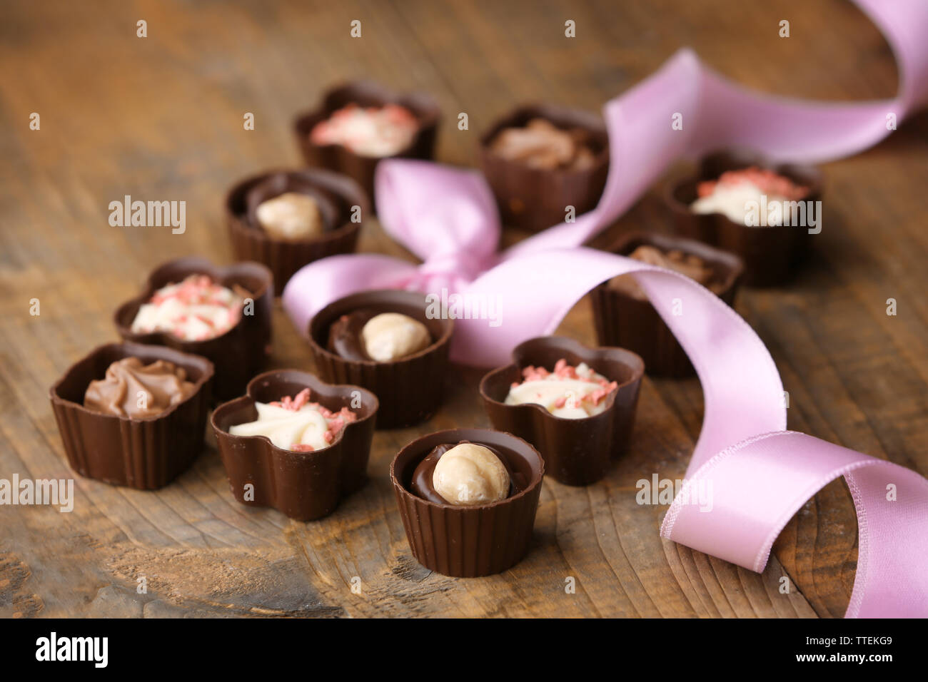 Set di cioccolatini con il nastro su un sfondo di legno Foto Stock
