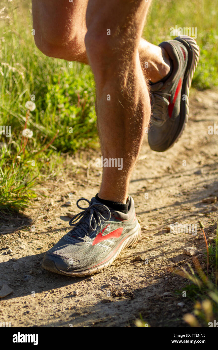 Uomo con muscolare di gambe indossando Brooks trail running Scarpe isolata  con uno sfondo naturale, early morning light Foto stock - Alamy