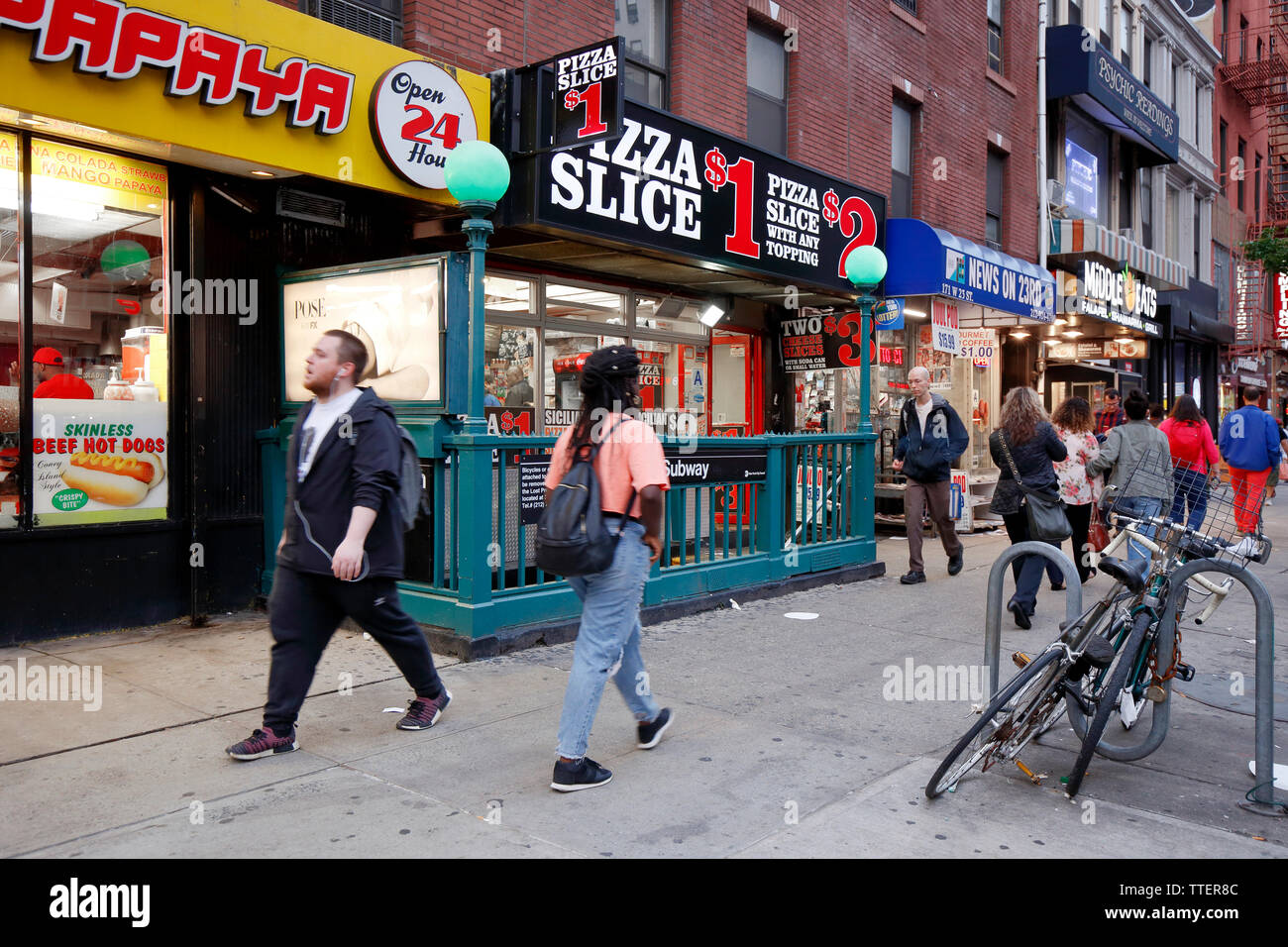 La gente a piedi passato fast food e ristoranti lungo la West 23rd Street e la 6th Ave a Manhattan, New York, NY. Foto Stock