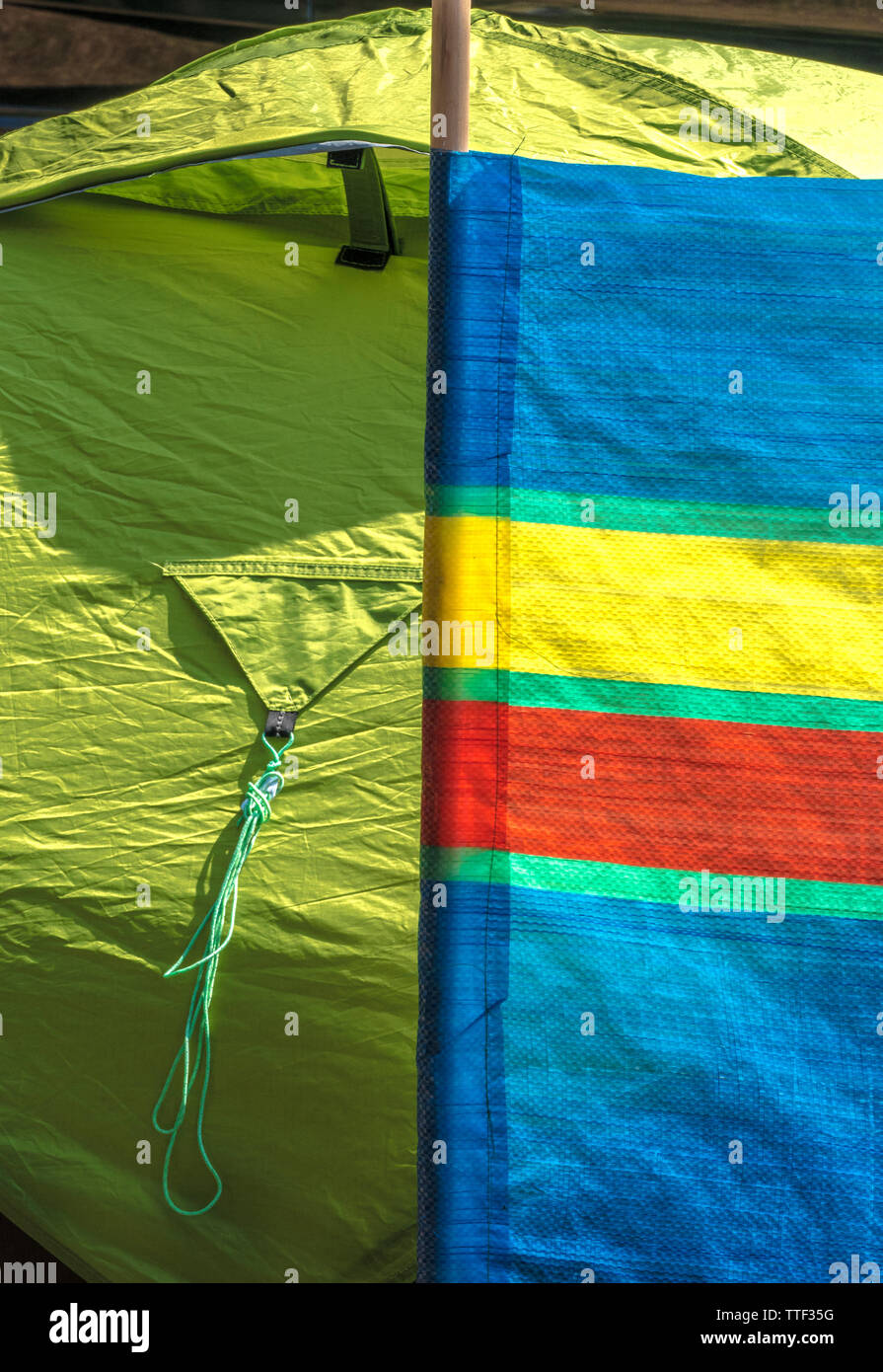 Un ingrandimento di una parte di un colorato striped il frangivento di offrire rifugio per la piccola tenda verde di fianco, in estate il sole. Inghilterra, Regno Unito. Foto Stock