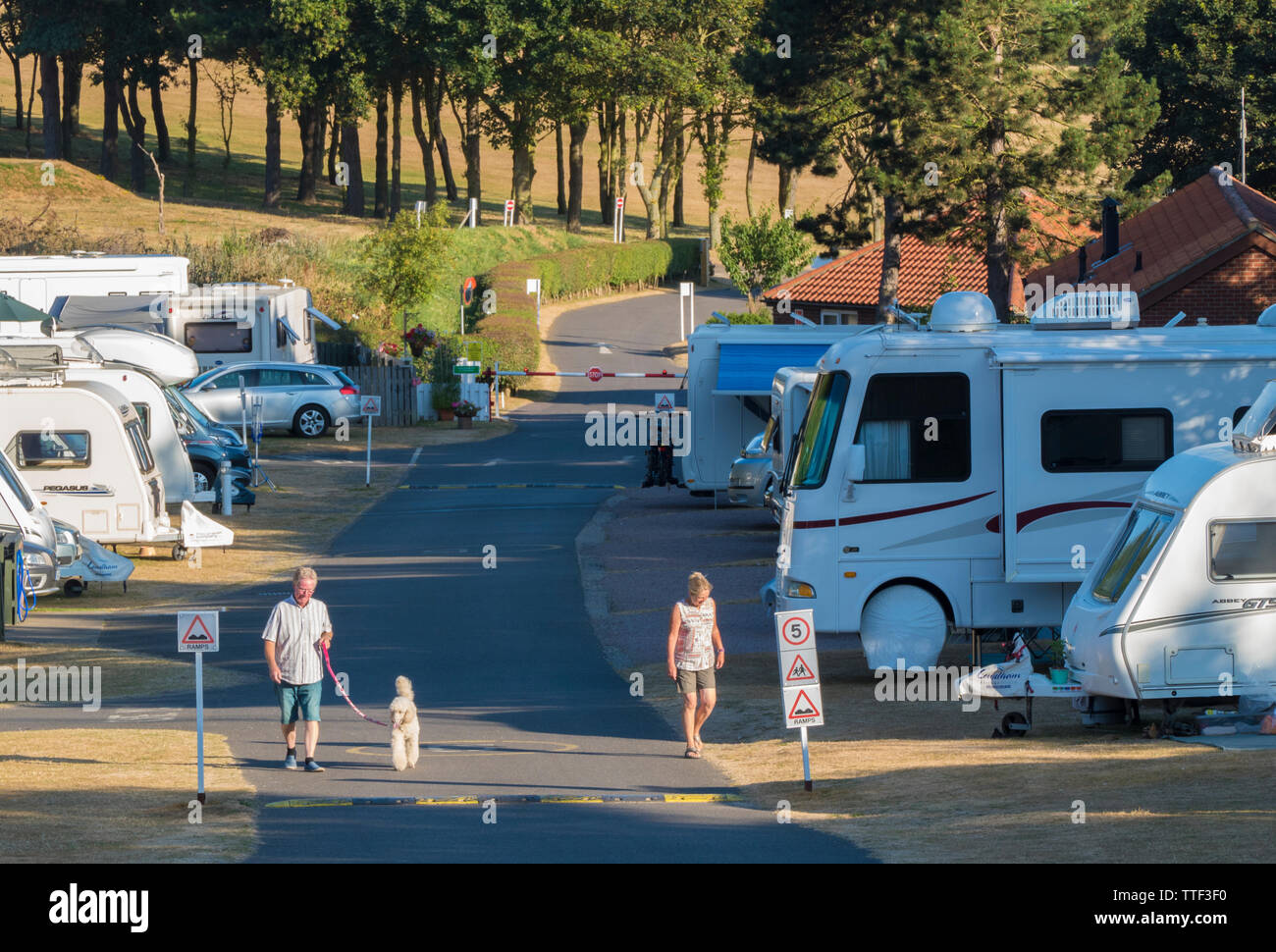 La gente a piedi attraverso un soleggiato caravan e camper Club sito (denominato Incleboro campi), West Runton, sulla Costa North Norfolk, Inghilterra, Regno Unito. Foto Stock