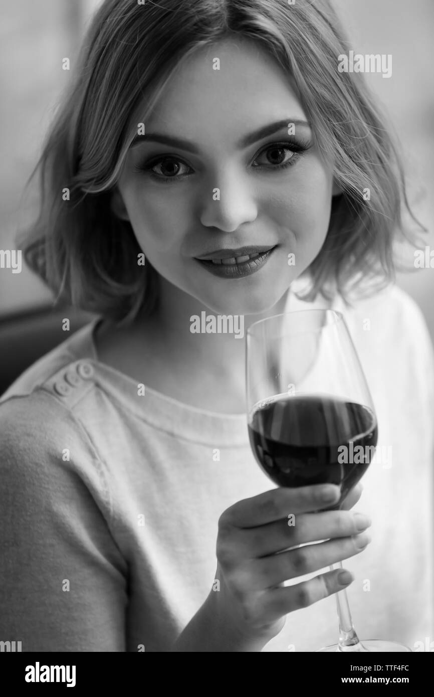 Giovane donna con un bicchiere di vino rosso in tonalità di grigio Foto Stock