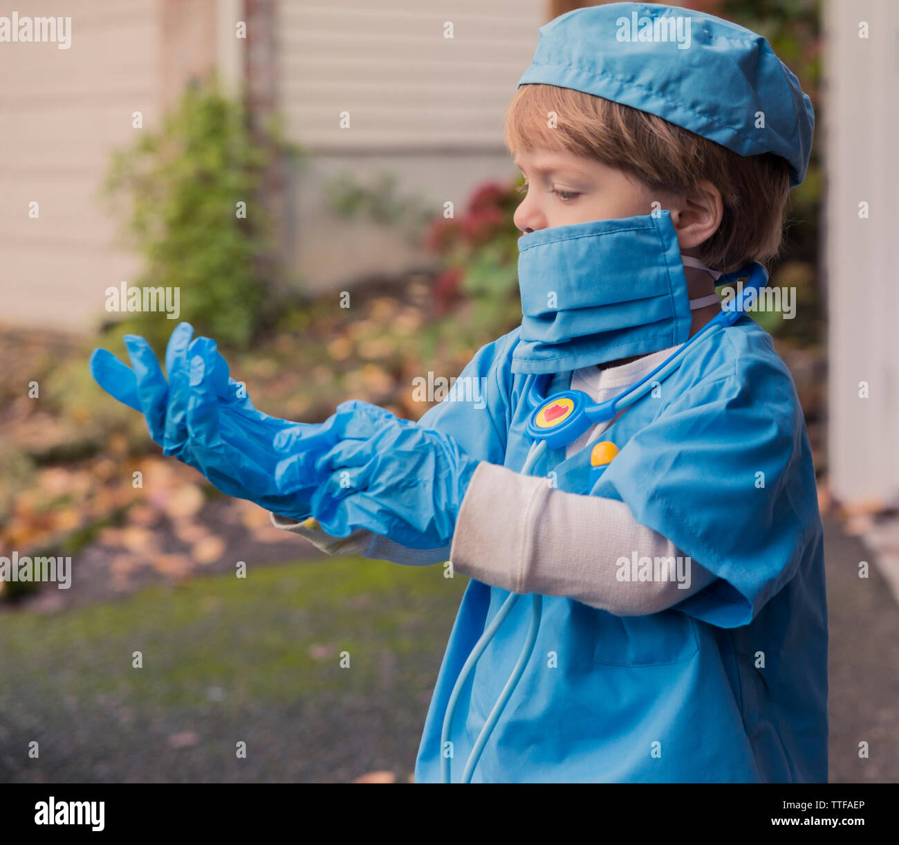 Ragazzo in costume medico indossando i guanti mentre in piedi in cantiere Foto Stock