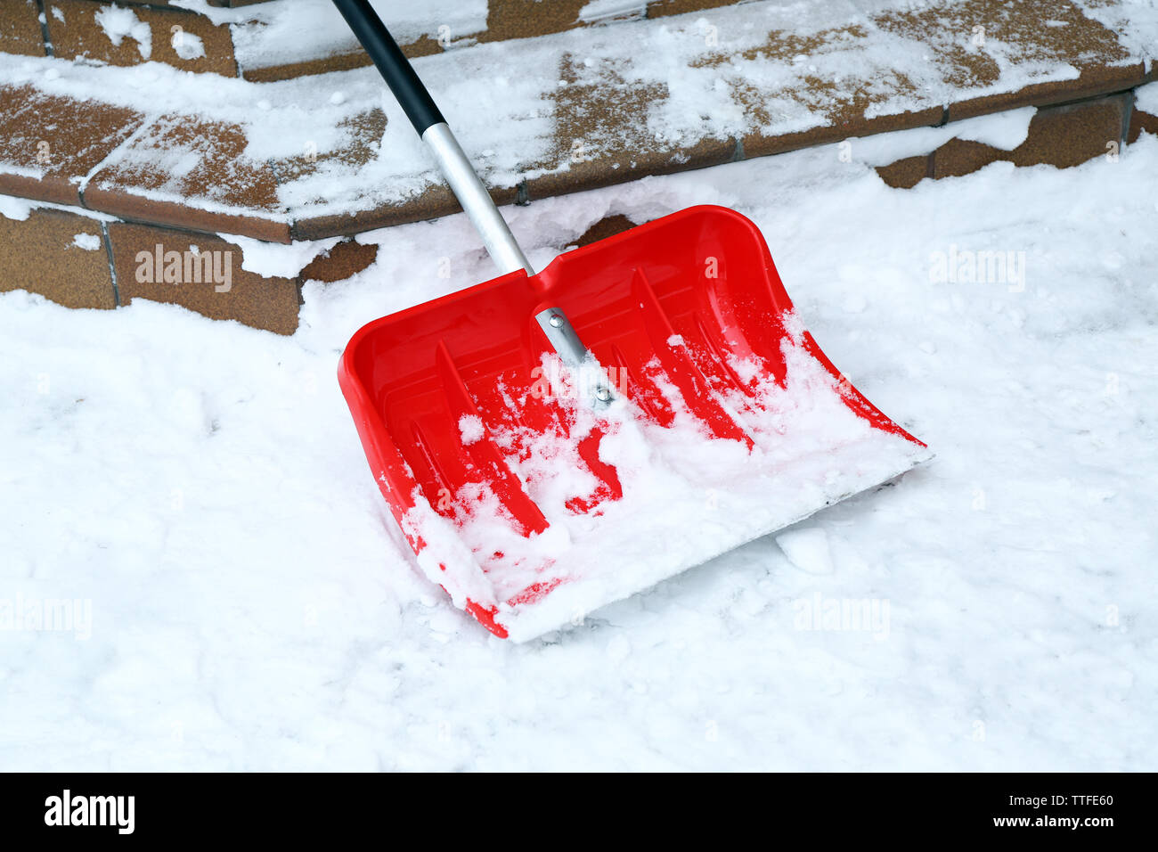 Pala di rosso per la rimozione della neve accanto a scale Foto Stock