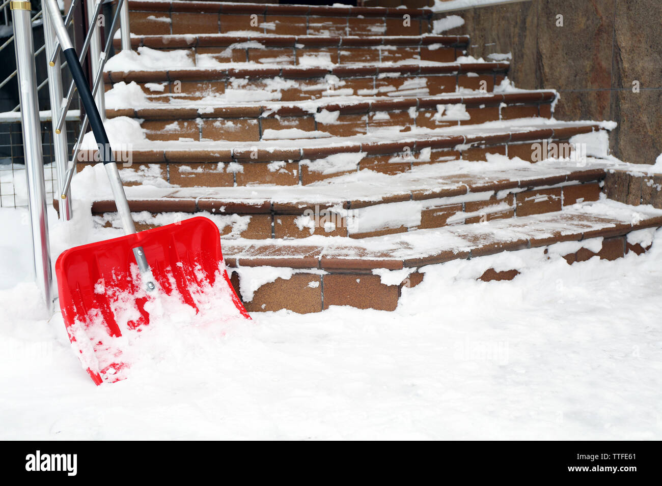 Pala di rosso per la rimozione della neve accanto a scale Foto Stock