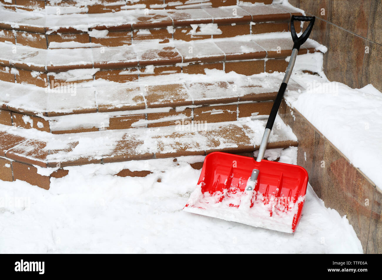 Pala di rosso per la rimozione della neve accanto a scale Foto Stock