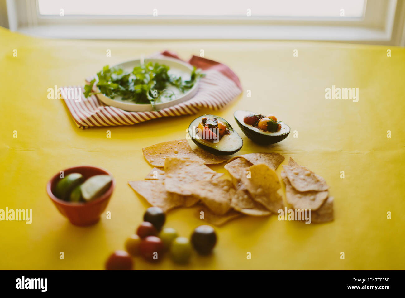 Close-up di salsa servita in un avocado con nacho chips sulla tabella di colore giallo Foto Stock