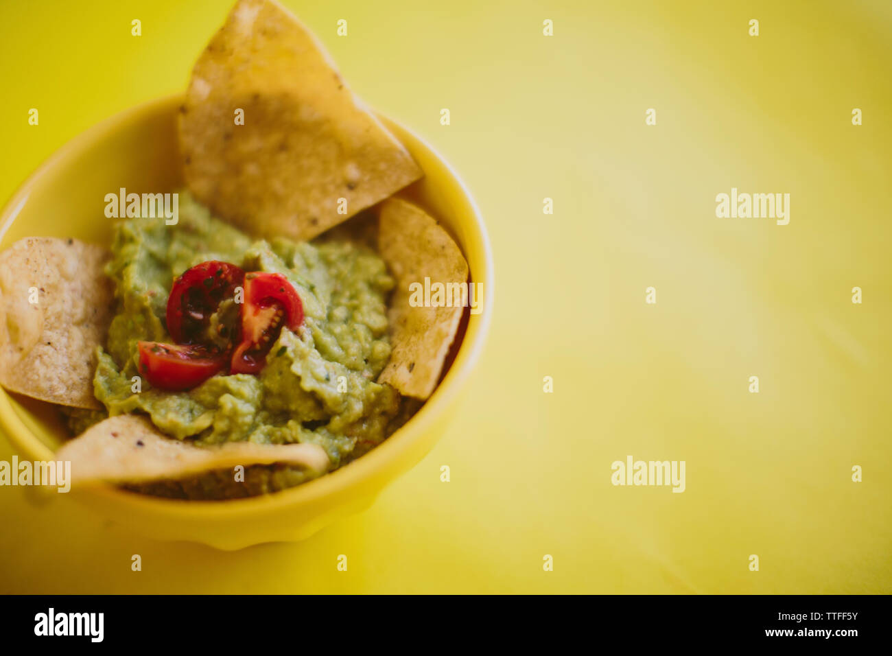 Close-up del guacamole con tortilla chips servito in tazza su sfondo giallo Foto Stock