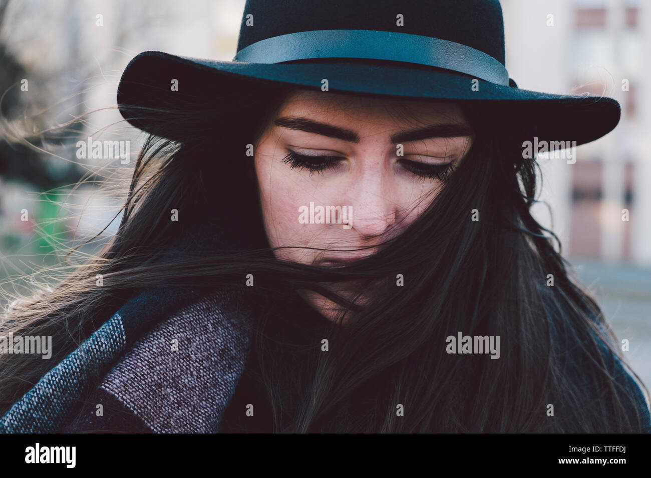 Close-up di pensosa giovane donna che indossa il cappello in città Foto Stock