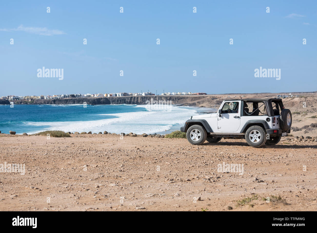 Bianco jeep 4x4 parcheggiata su una scogliera con una spiaggia in background Foto Stock