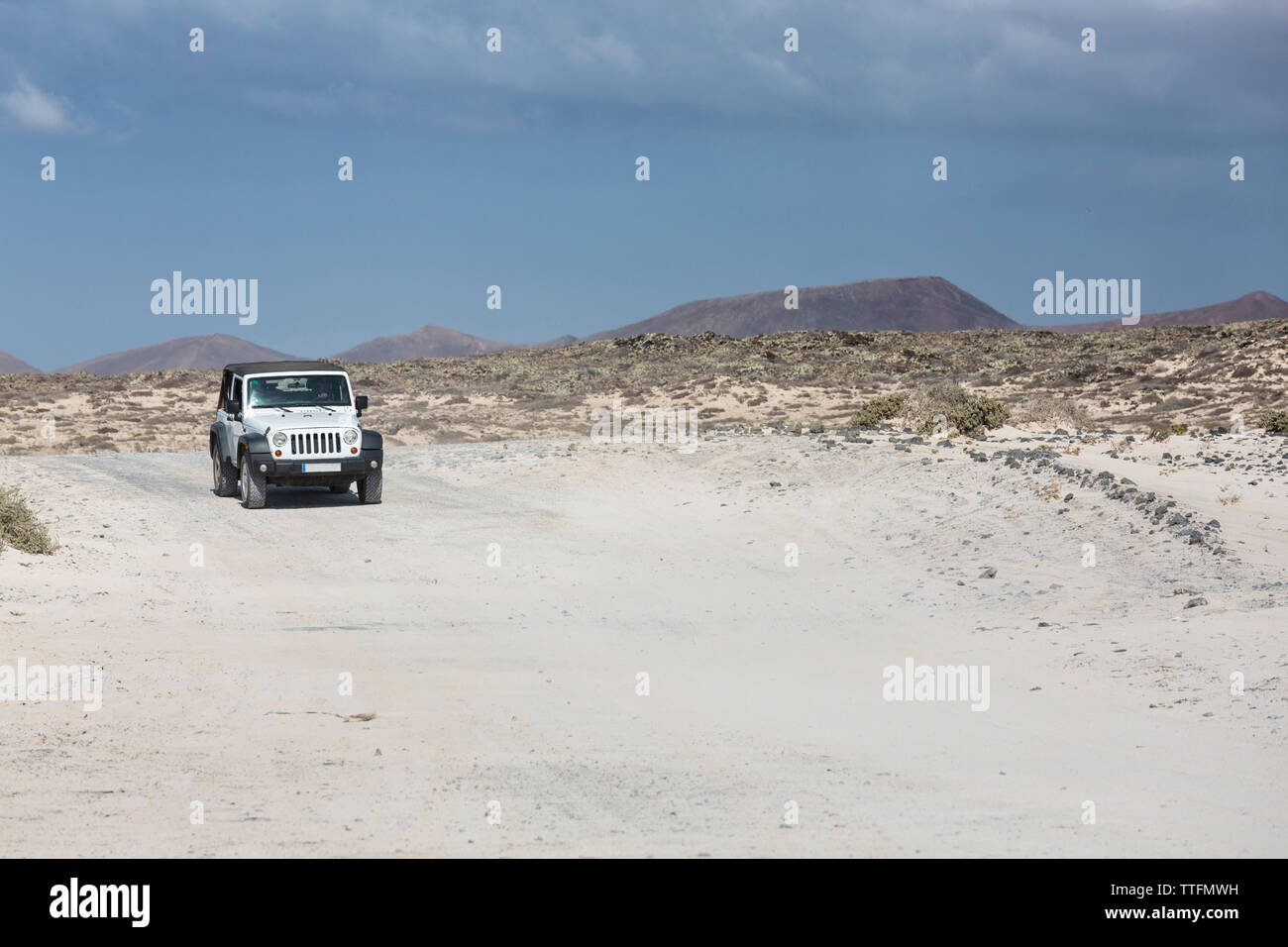 Bianco jeep 4x4 la guida vuota strada sporca nel deserto paesaggio vulcanico Foto Stock