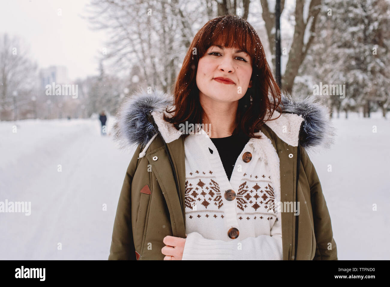 Ritratto di donna con redhead permanente sulla coperta di neve campo nel parco Foto Stock