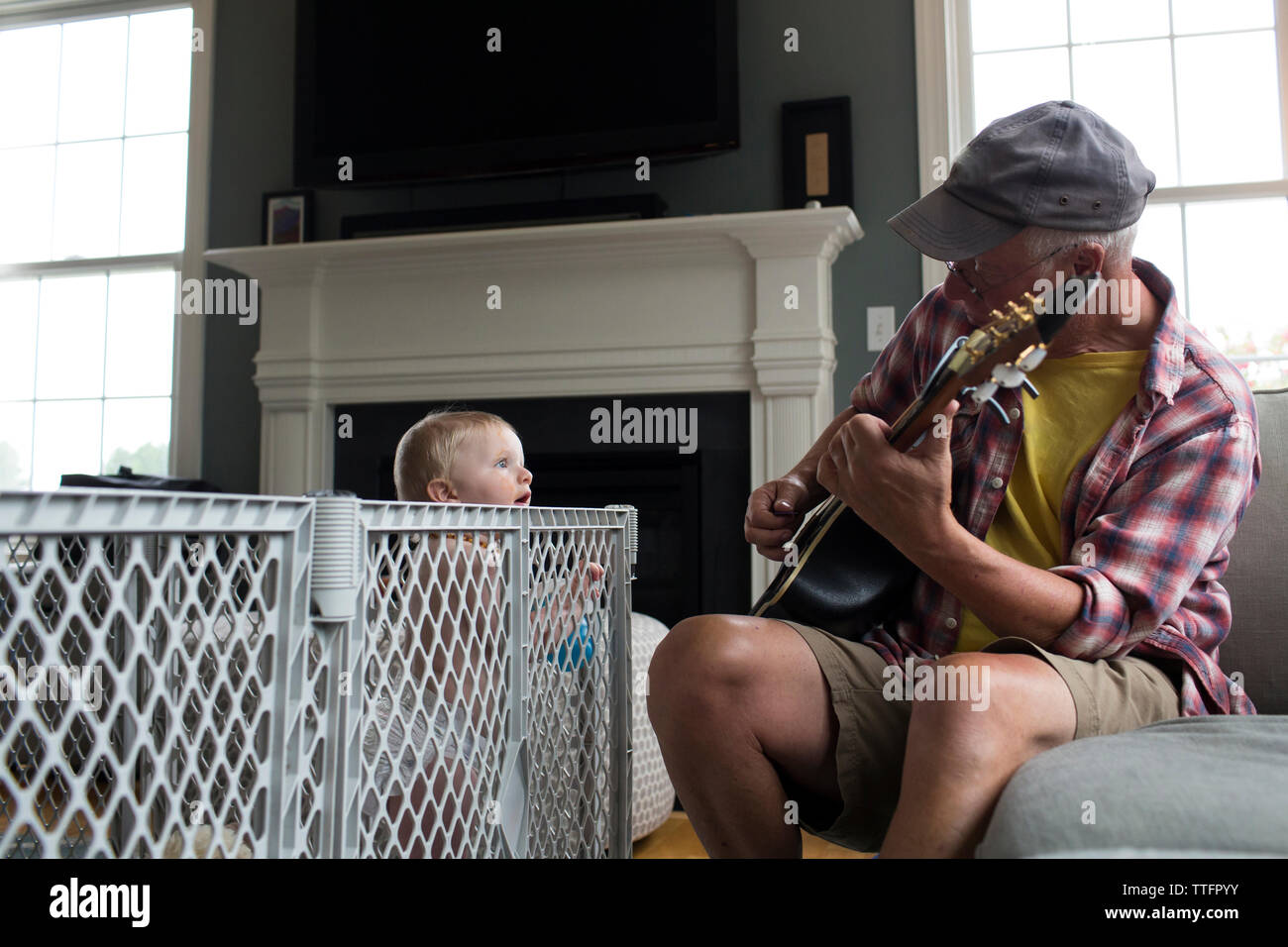Nipote guardando il nonno la riproduzione di strumento a corda a casa Foto Stock