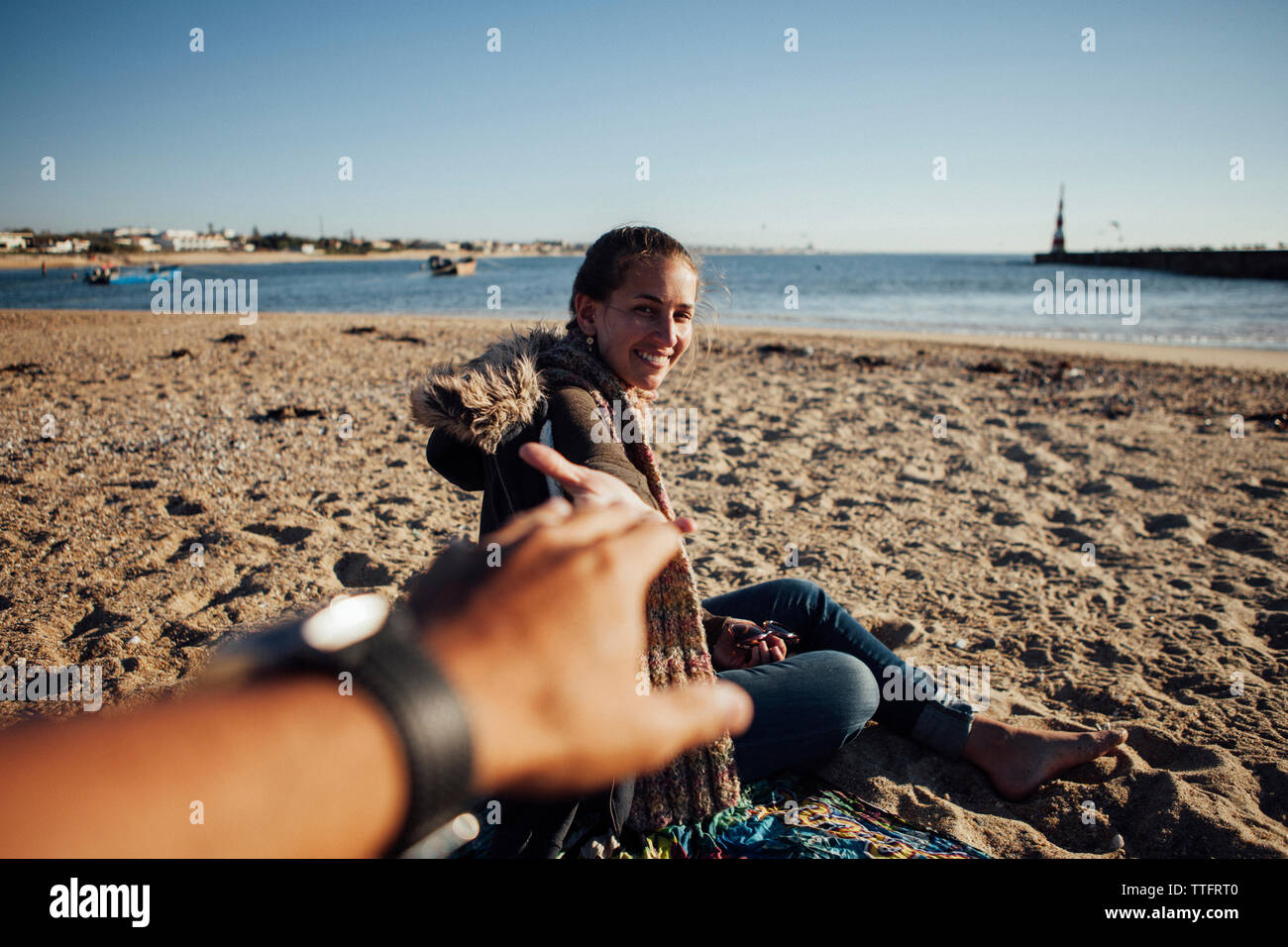 Immagine ritagliata della donna azienda man mano mentre seduto sulla sabbia in spiaggia Foto Stock