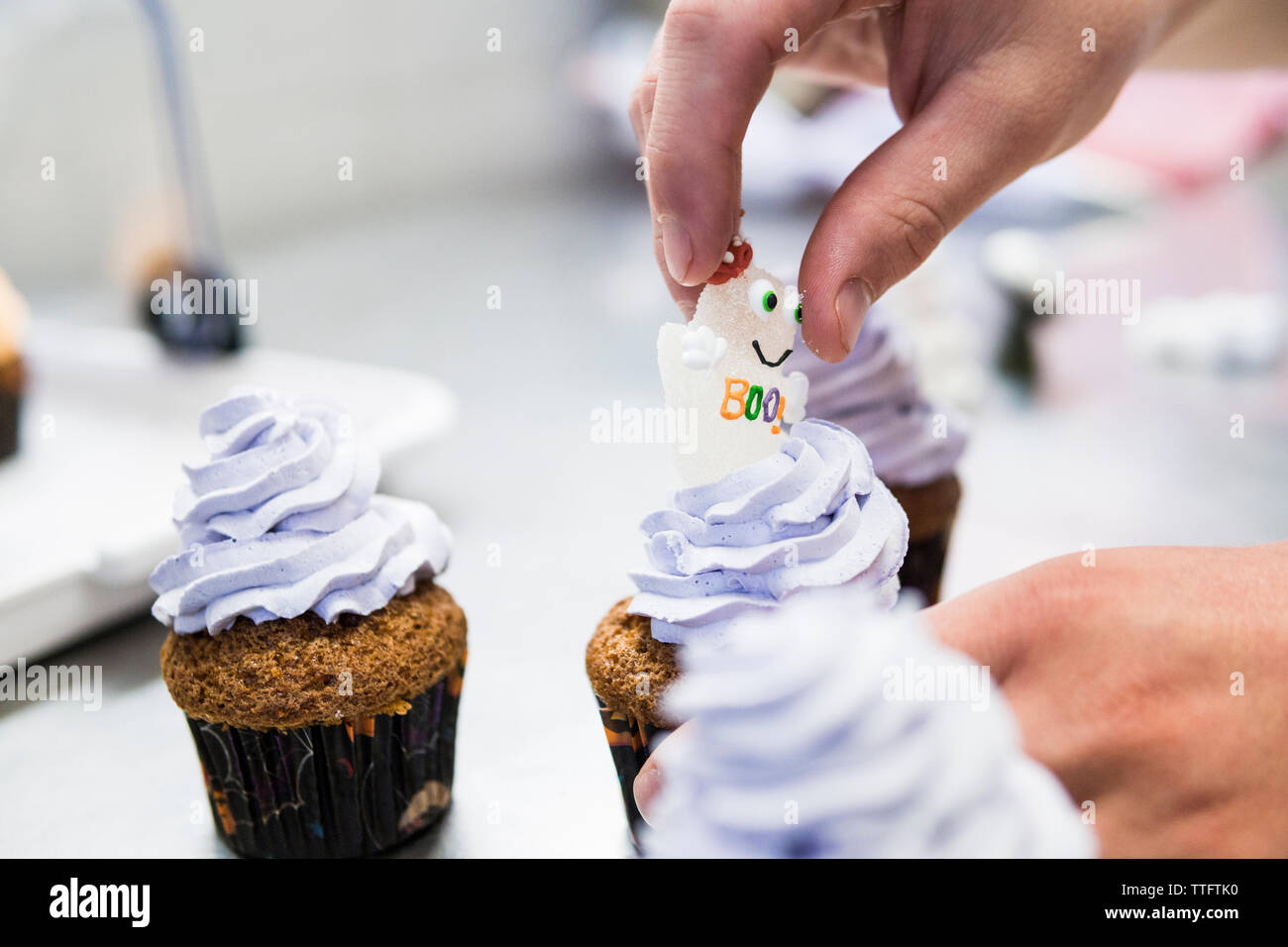 Mano del pasticciere aggiungere un dolce zucchero ghost su un cupcake di halloween Foto Stock