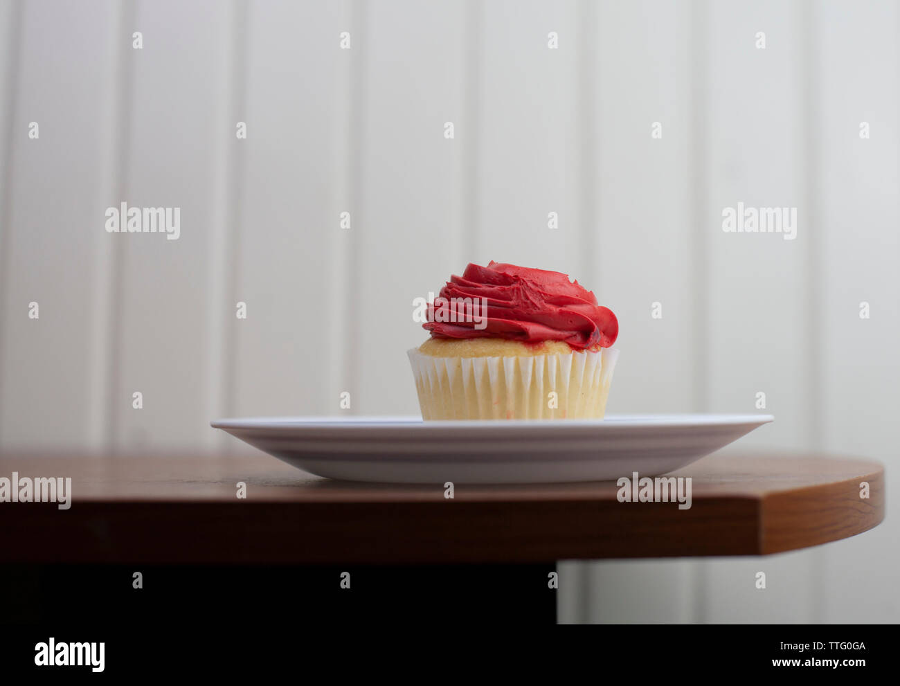 Red Iced Vanilla Cupcake su un bianco piatto Foto Stock