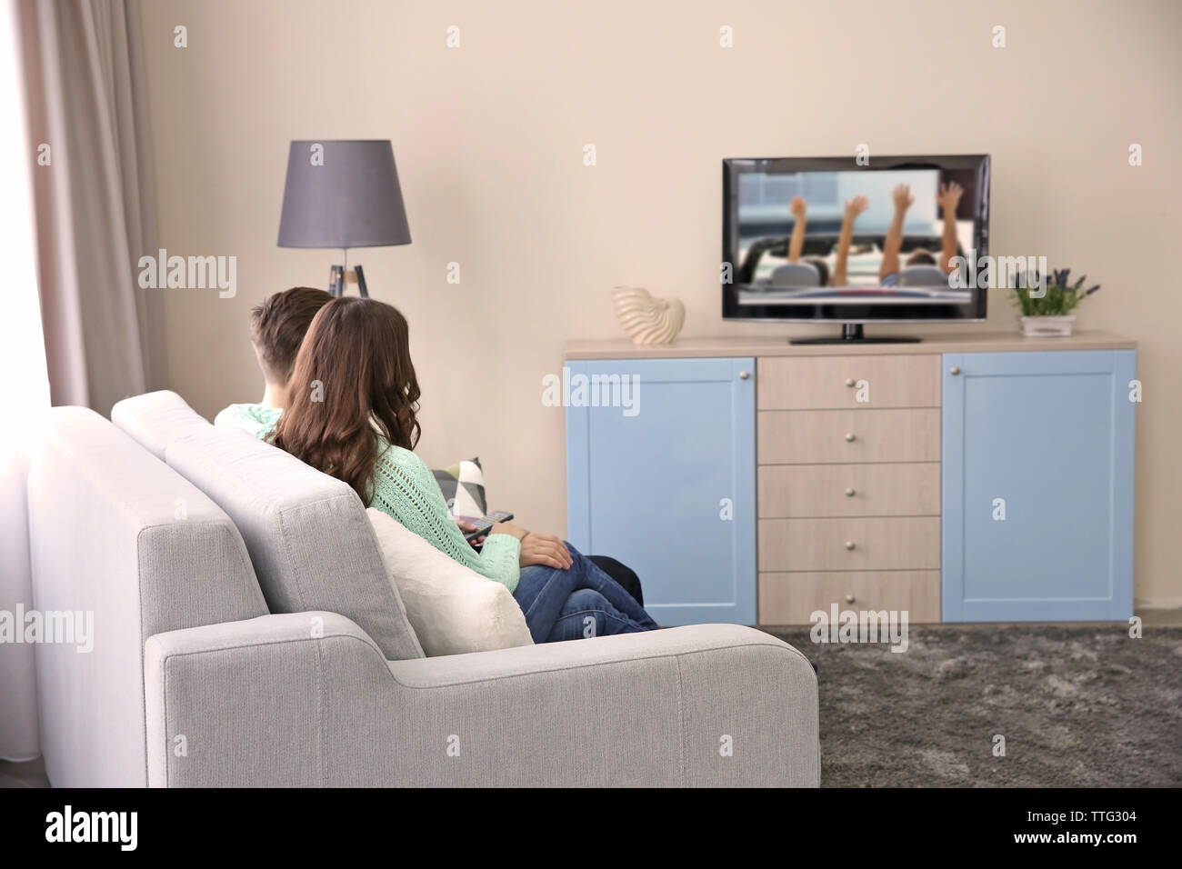 Coppia giovane guardare la TV su un divano a casa Foto Stock
