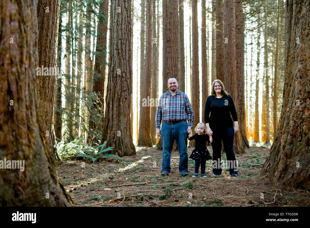 Il padre e la madre con il loro bambino di età compresa tra la figlia di stand nella foresta Foto Stock