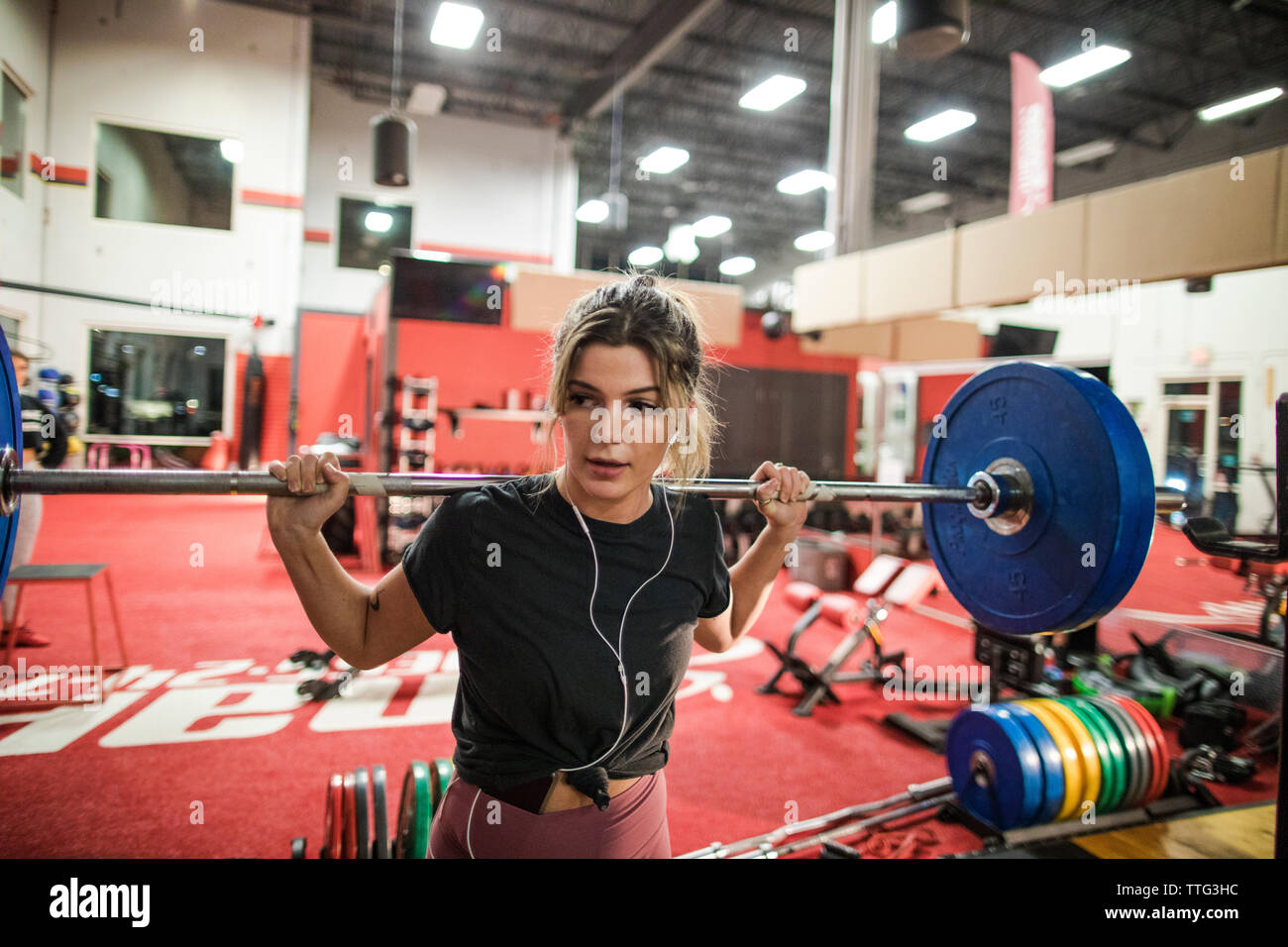 Donna che mantiene barbell con piastre di peso nel centro fitness Foto Stock