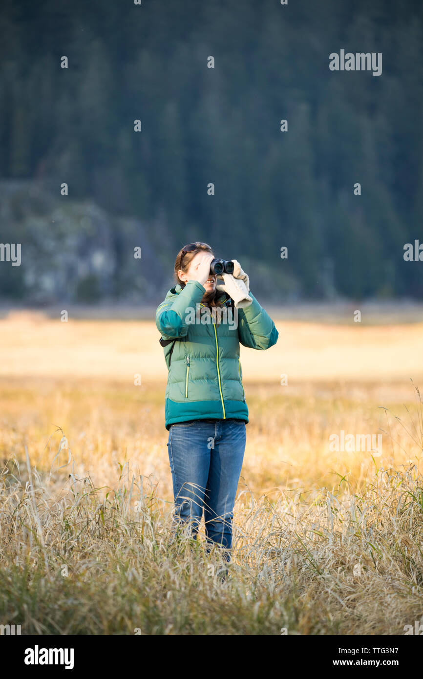 Giovane donna di birdwatching con il binocolo Foto Stock