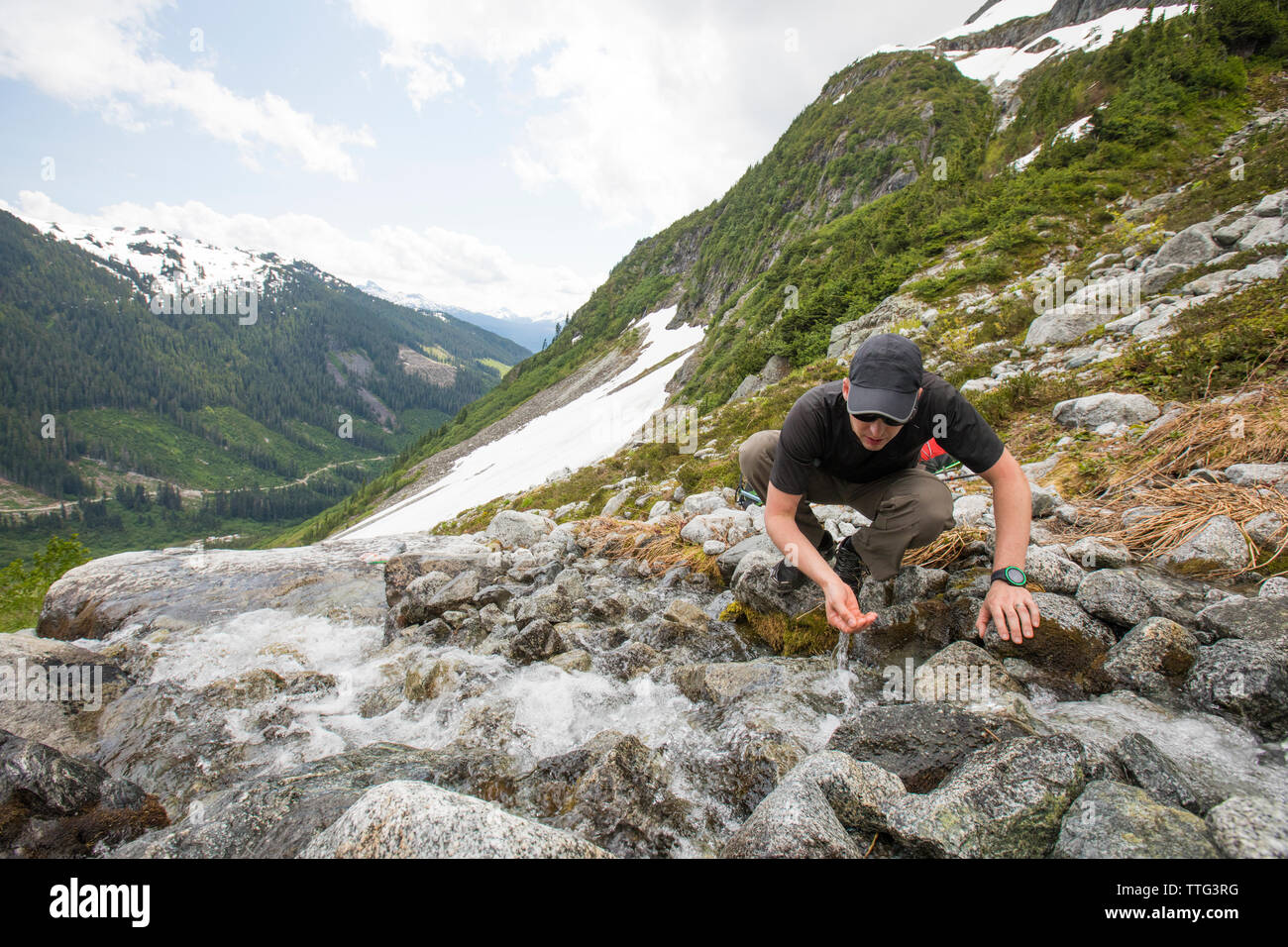 Alpinista di acqua dolce bevande dal torrente di montagna. Foto Stock