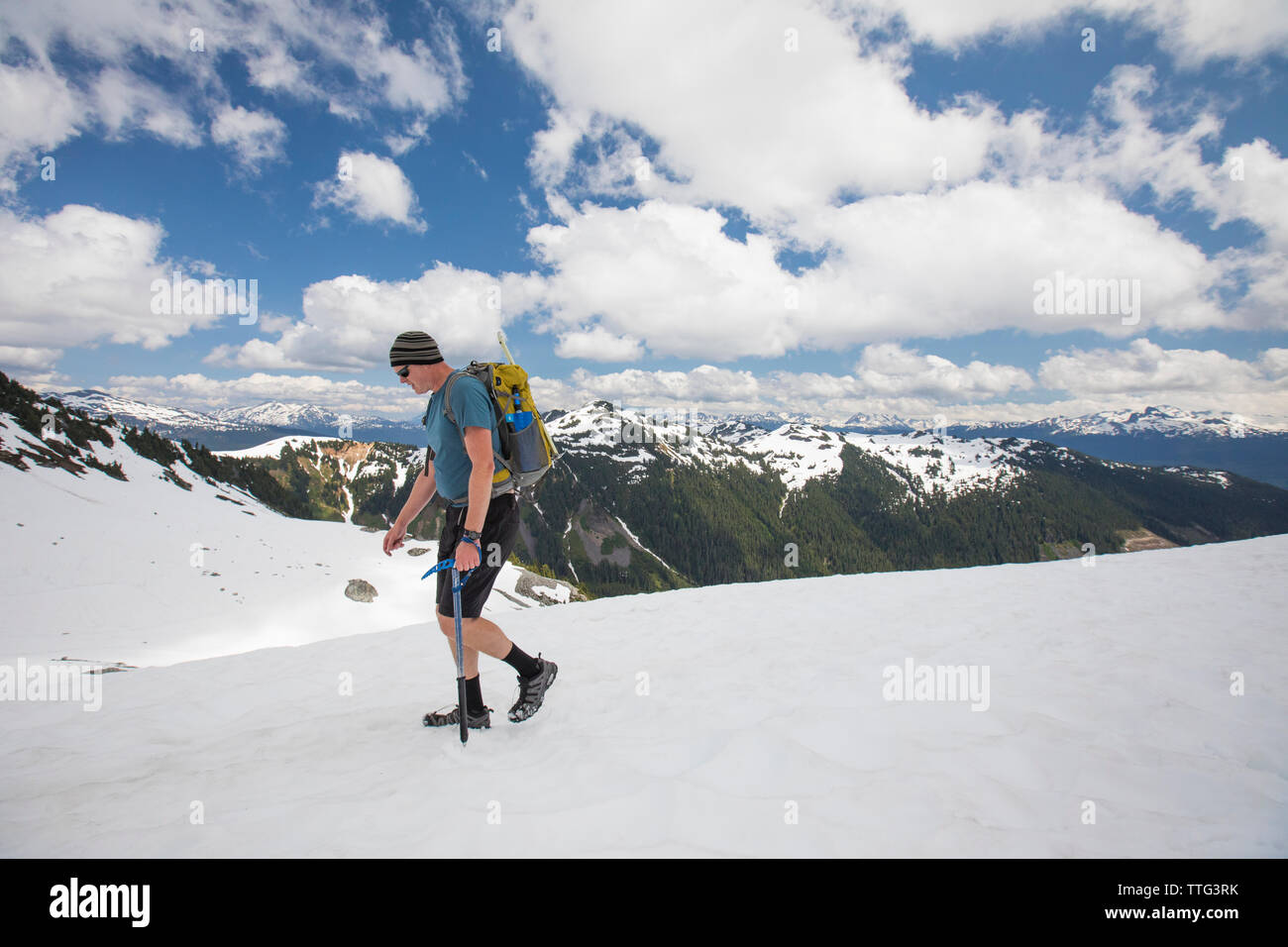 Backpacker escursioni attraverso snowfield al di sotto del picco di cipressi, B.C. Foto Stock