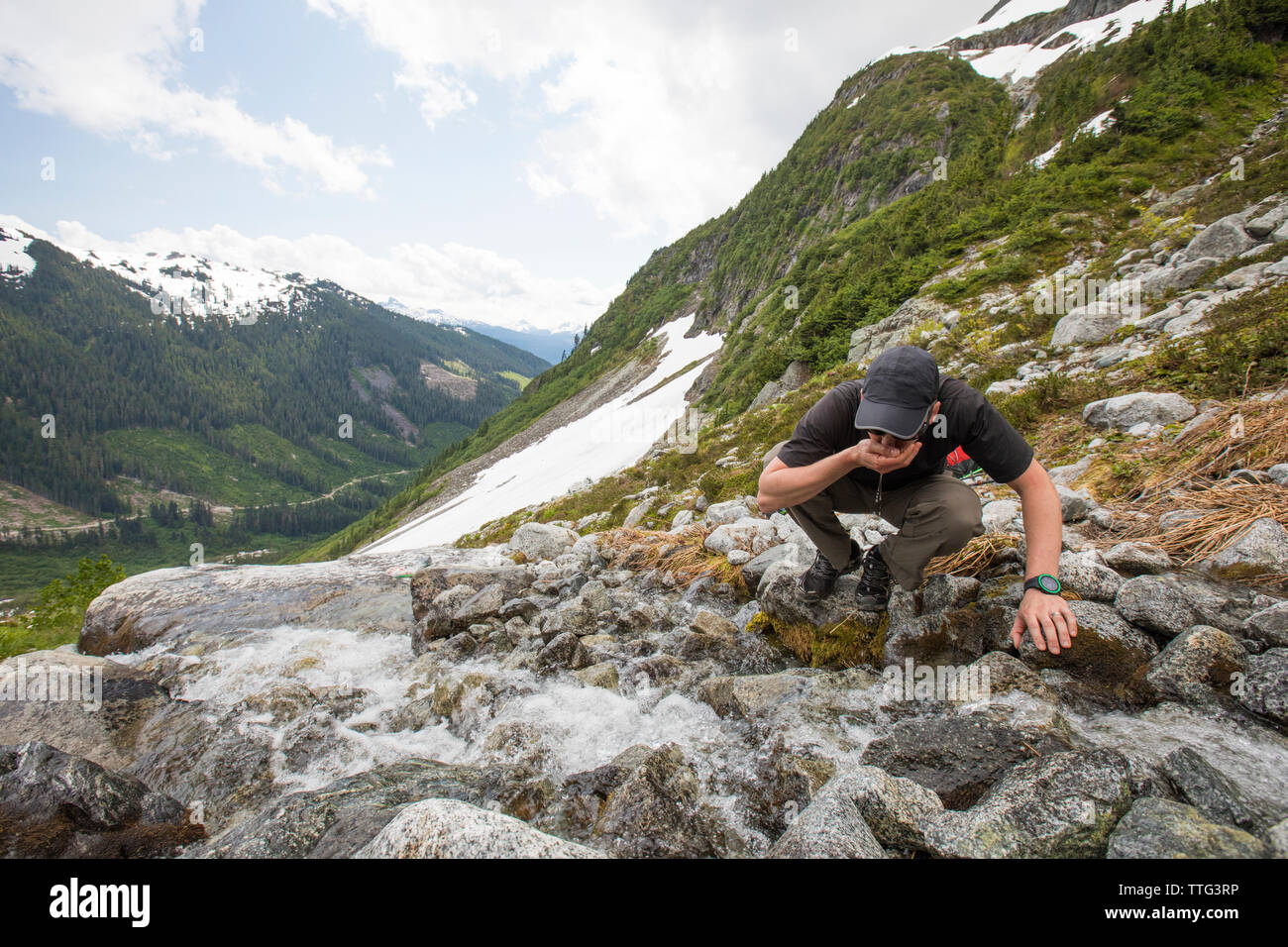 Escursionista bevande acqua dolce proveniente da torrente di montagna (Roe Creek), B.C. Foto Stock
