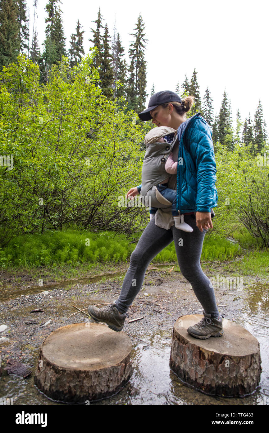 Madre attivo escursioni attraverso cicli di registro per evitare la pista bagnata. Foto Stock