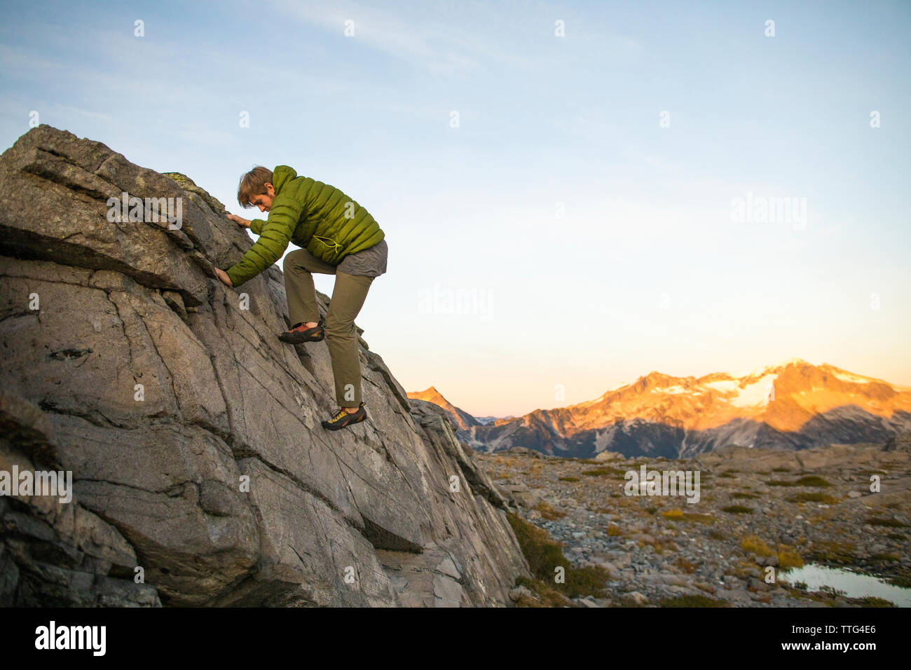 Basso angolo vista del giovane uomo bouldering in Costa montagne, B.C. Foto Stock
