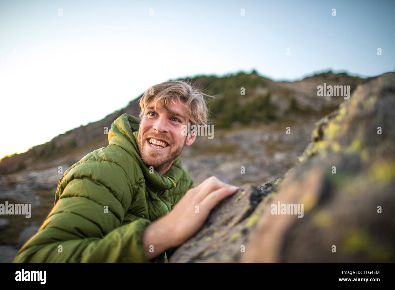 Vista laterale di uomo felice arrampicata su roccia. Foto Stock