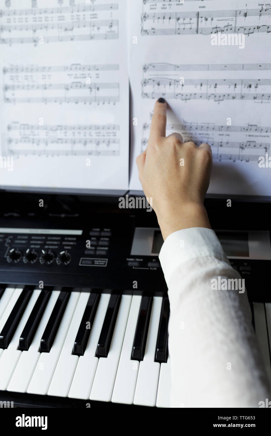 Ritagliate la mano della donna di toccare nota musicale mentre si pratica il pianoforte a casa Foto Stock
