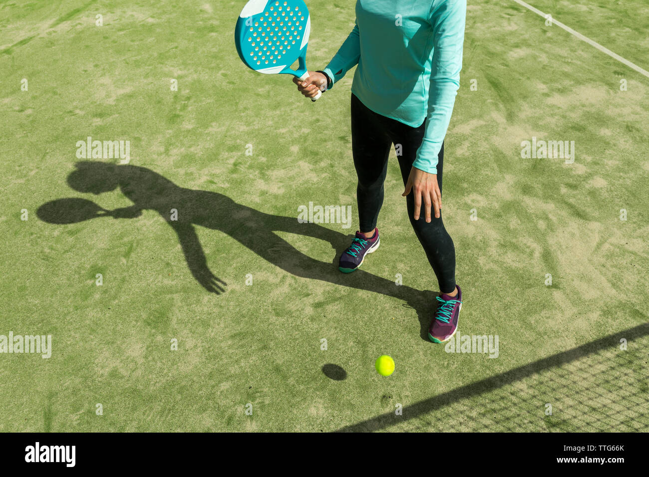 Sezione bassa della donna a giocare a paddle tennis su corte durante la giornata di sole Foto Stock