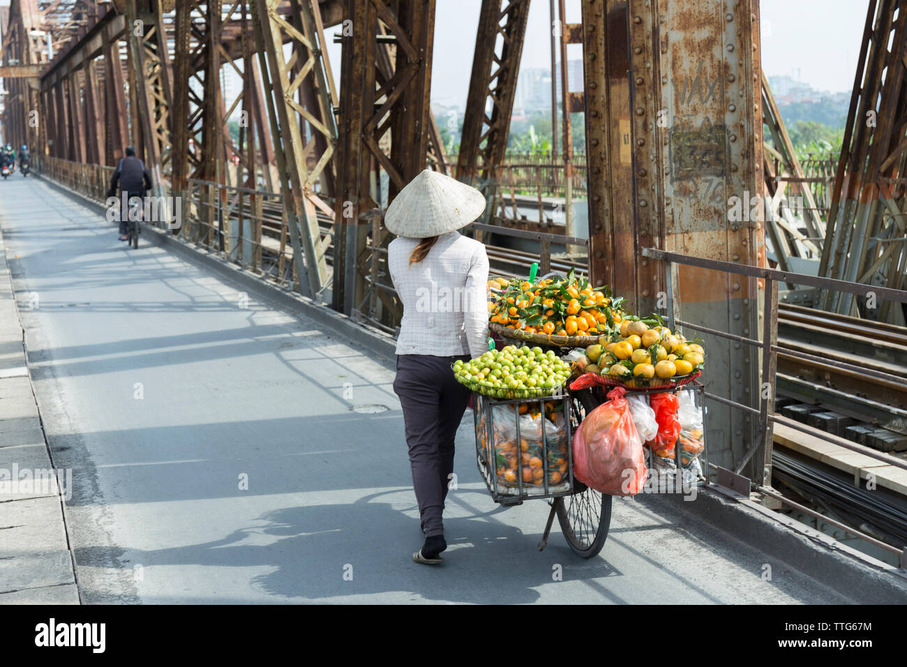 Donna vietnamita che porta frutti sulla sua bicicletta Foto Stock