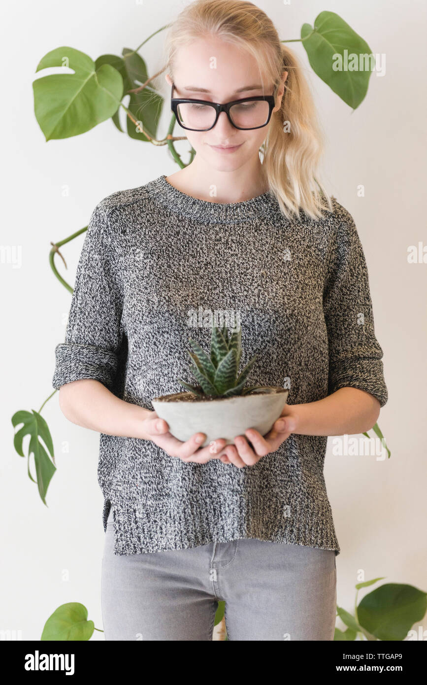 donna d'affari che tiene la pianta in cemento nell'ufficio creativo Foto Stock