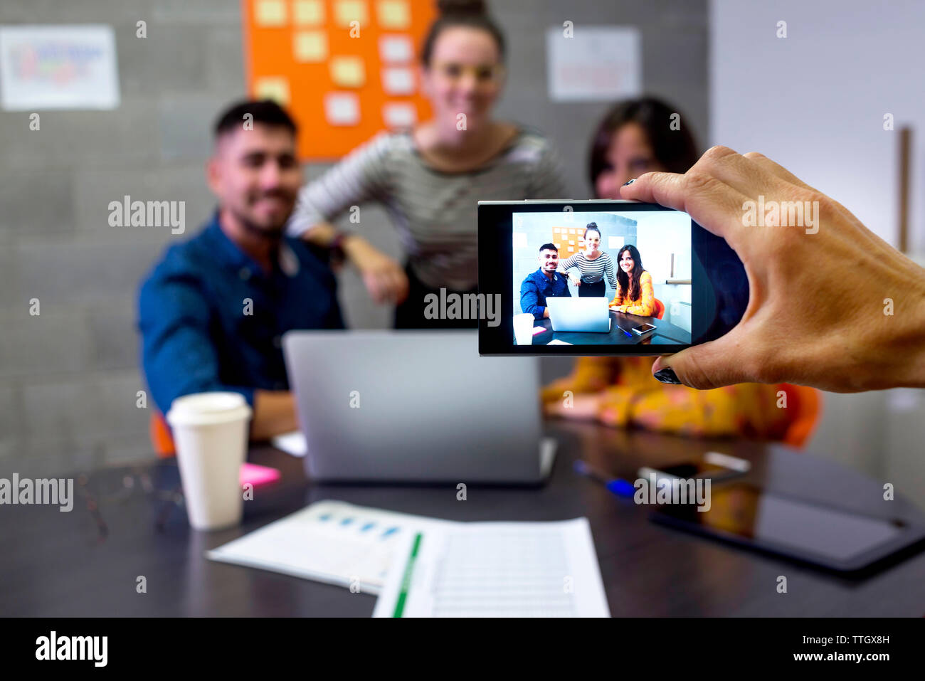 Tagliato a mano imprenditrice di fotografare i colleghi con il cellulare in sala riunioni Foto Stock