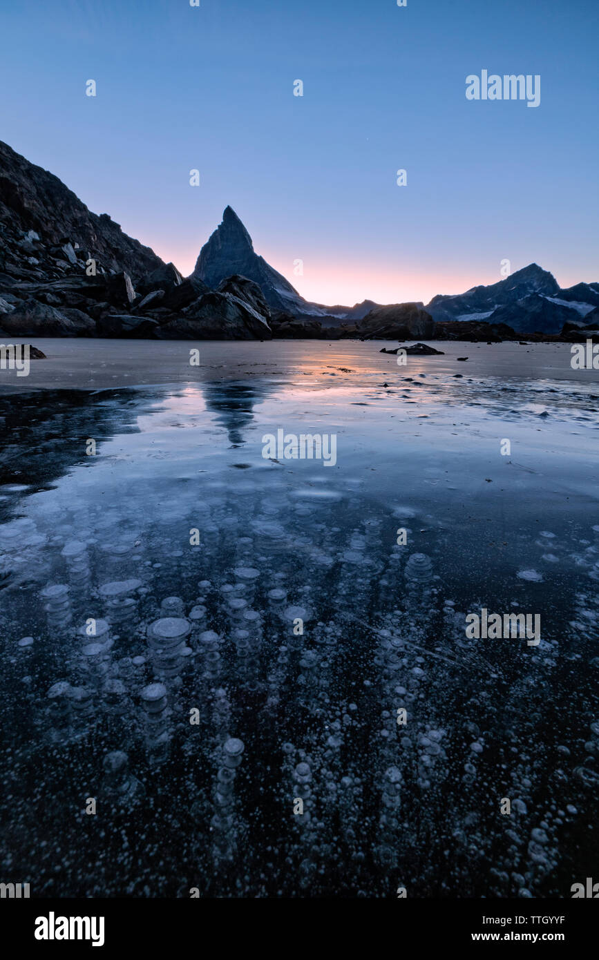 Matterhorn specchiato in Riffelsee ricoperto di ghiaccio bolle Foto Stock