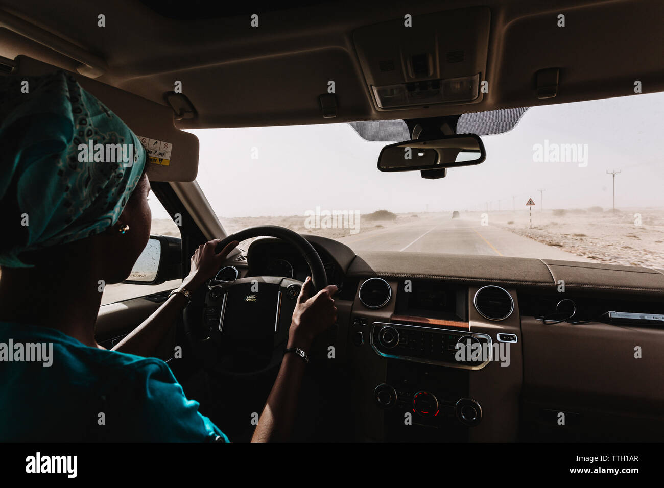 Una donna comanda un veicolo fuoristrada su una strada nel deserto Foto Stock