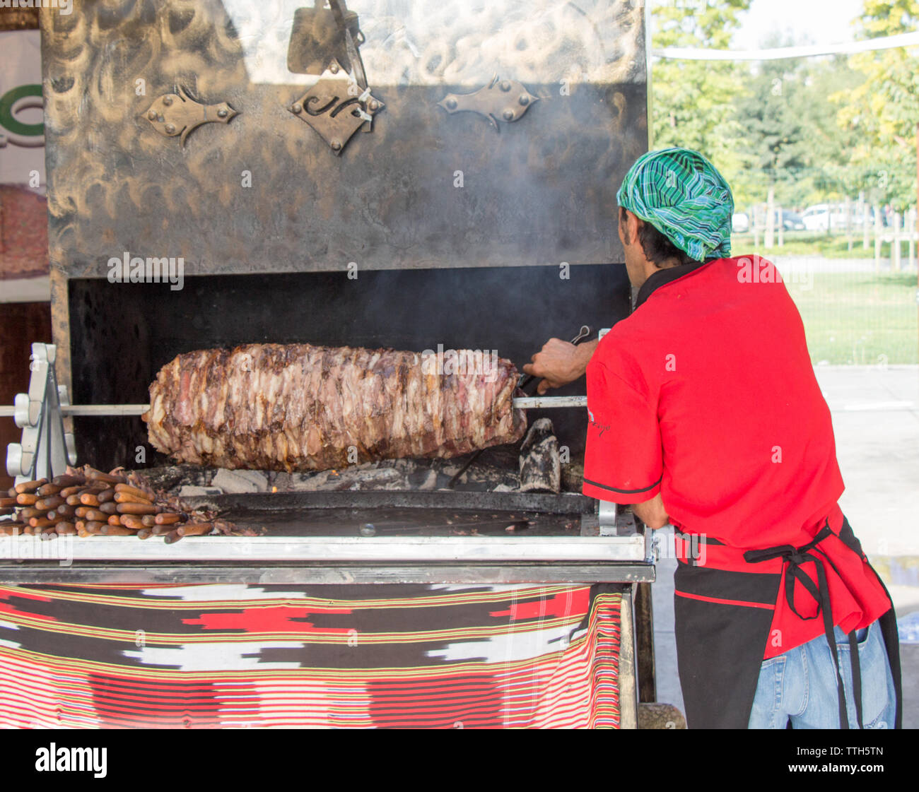 Lo Chef vestito di rosso il taglio turco Kebab Cag nel display Foto Stock