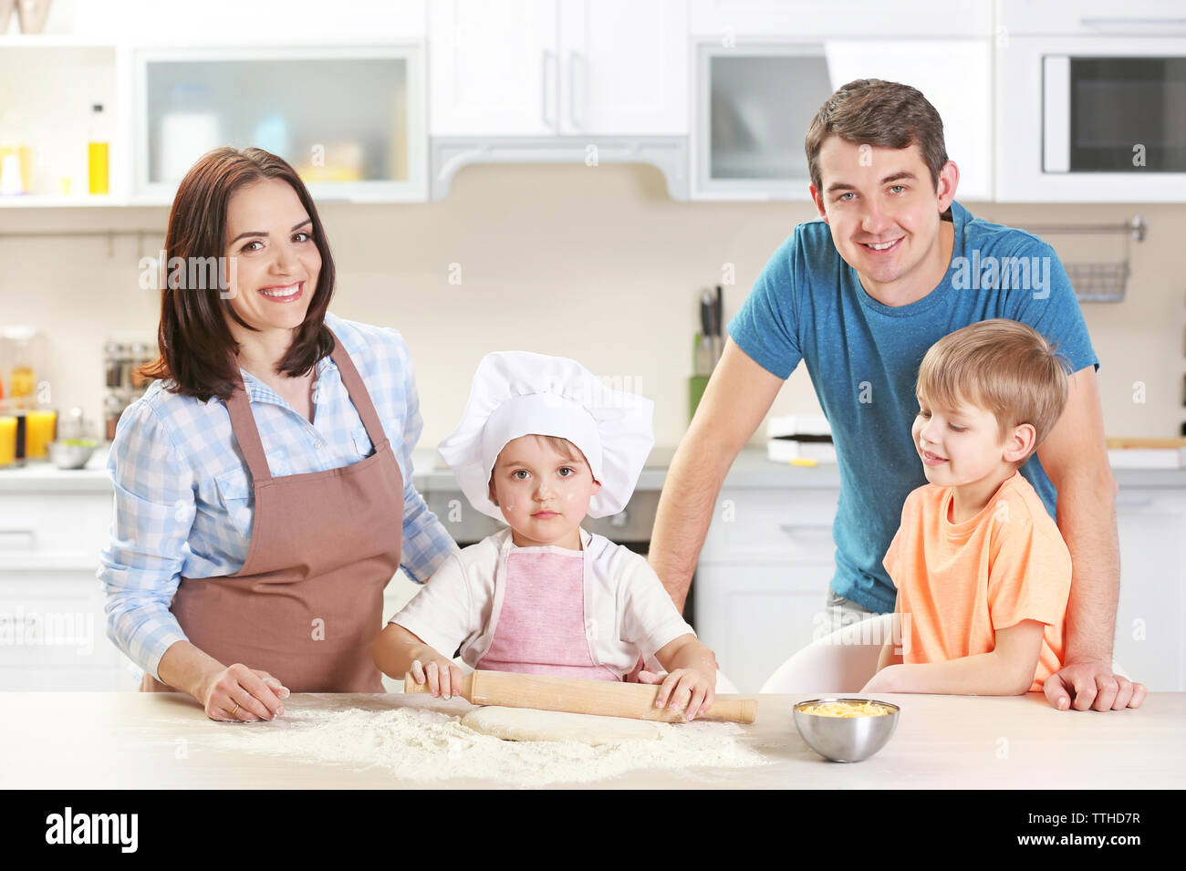 I giovani genitori a guardare la loro figlio a stendere un impasto, close up Foto Stock