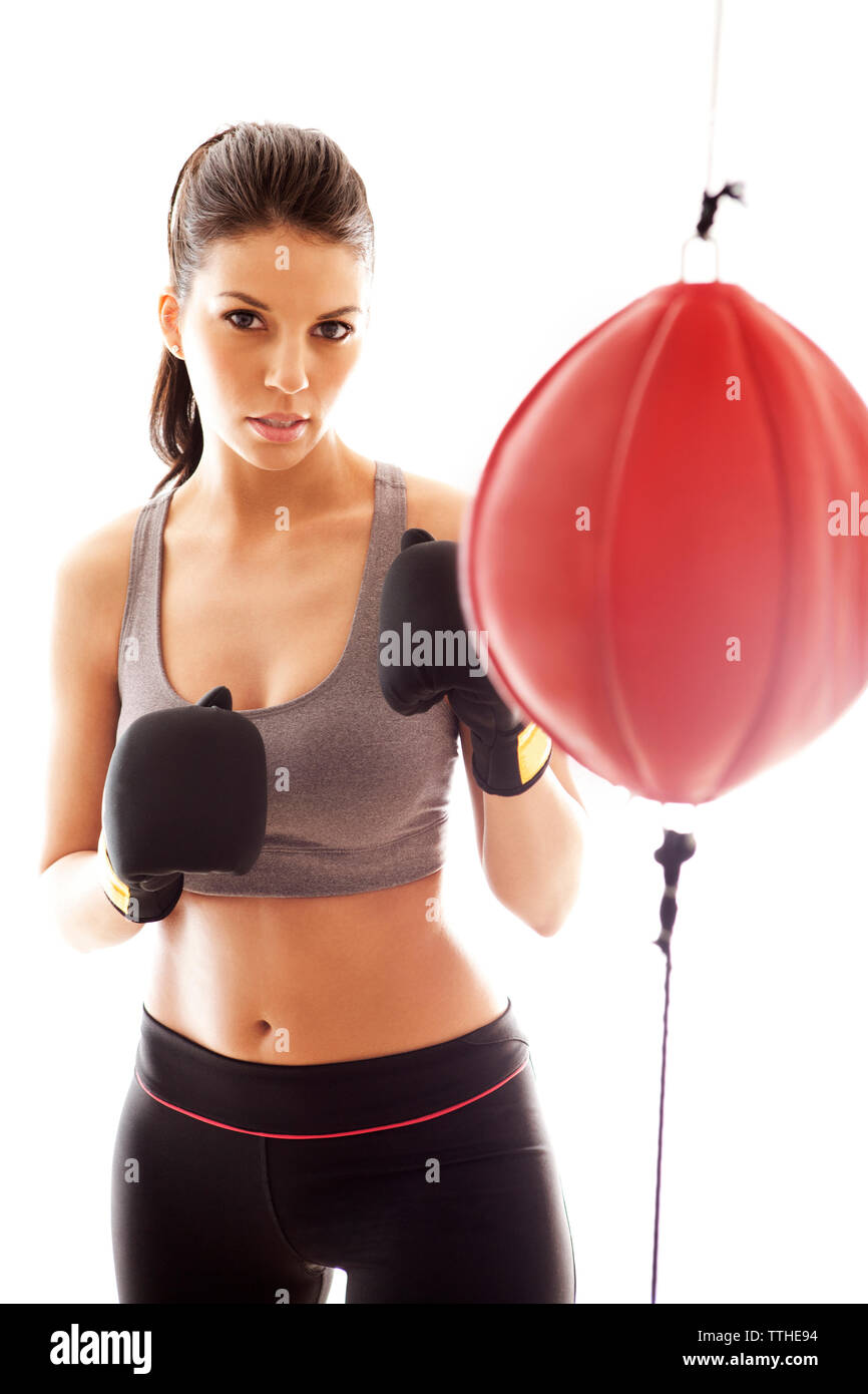 Ritratto di fiducioso sportive in piedi dal sacco da boxe contro uno sfondo bianco Foto Stock