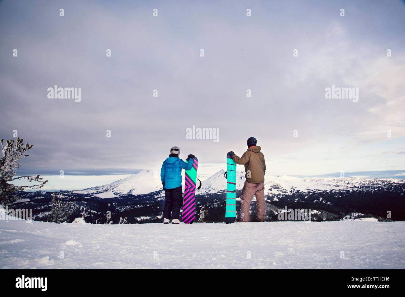 Amici holding snowboard mentre permanente sulla coperta di neve campo Foto Stock