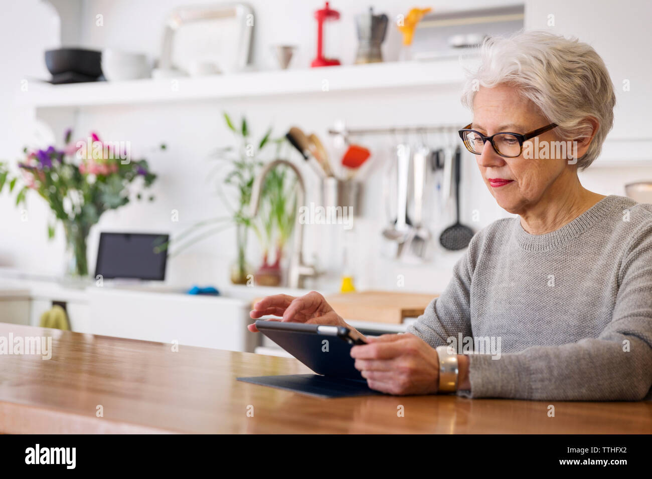 Donna che utilizza computer tablet stando seduti a tavola Foto Stock
