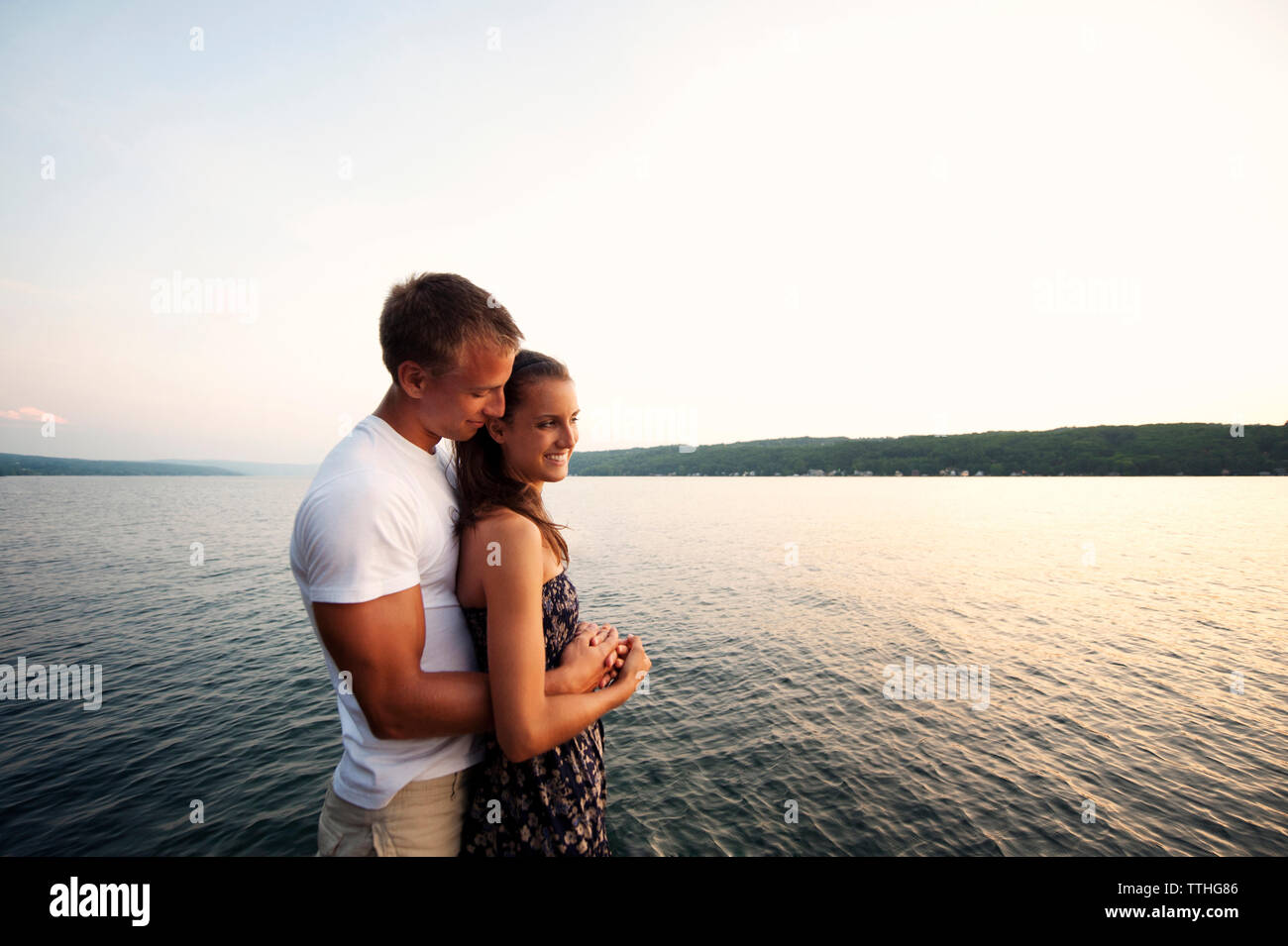 Coppia romantica in piedi dal lago contro il cielo chiaro Foto Stock