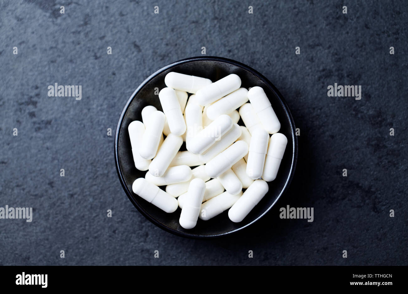 Arginina alfa-chetoglutarato (AAKG) capsule. Bodybuilding integratori alimentari in pietra scura sullo sfondo. Vista dall'alto. Copia dello spazio. Foto Stock